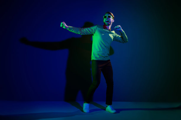 年轻男子全尺寸照片，面带快乐积极的笑容，在夜总会派对上兴奋地跳舞，背景为深色，独立拍摄图片下载