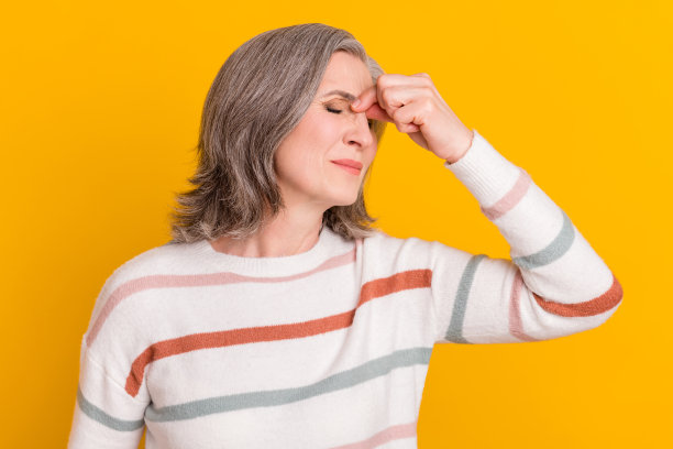 一位戴着白色假发的悲伤老妇人，手捂着鼻子，穿着毛衣，孤立在黄色背景上，作为个人资料照片图片下载