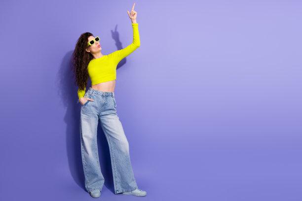 身穿霓虹衬衫和牛仔裤的年轻女子自信地站在紫色背景前，展现时尚休闲生活方式和有趣的风格，适合作为充满活力的营销图片图片下载