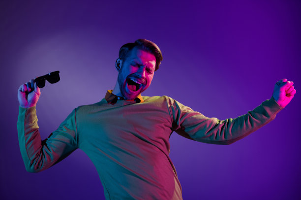 照片肖像：喜出望外的男人在夜总会迪斯科舞厅放松跳舞，孤立在紫色背景上图片下载