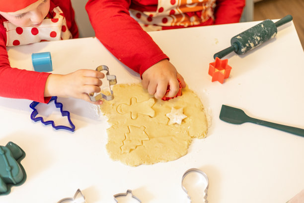 孩子们在充满节日气氛的厨房里，使用饼干模具和面团享受假日烘焙的乐趣图片下载