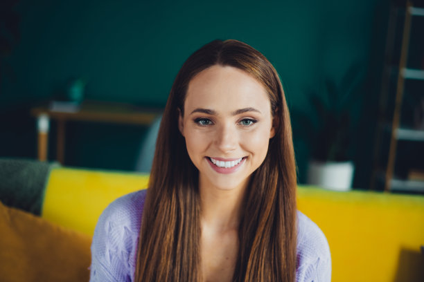 一位年轻的棕发女子，笑容温暖，身处色彩缤纷的客厅，适合生活方式、家居内饰和房地产图库照片图片下载