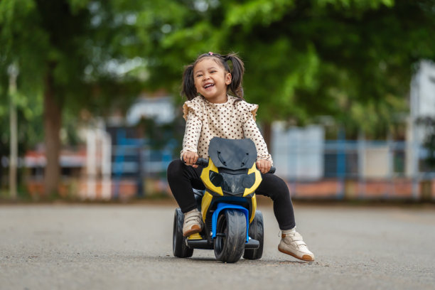 小女孩在公园里骑着电动玩具摩托车图片下载