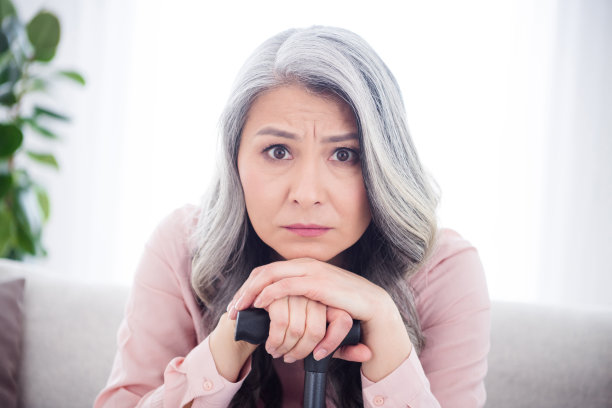 照片：一位不开心、孤独的老妇人在室内（家中、公寓里）拄着手杖，心情糟糕。图片下载