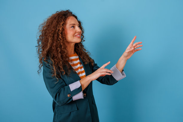 长卷发女子做出手势，仿佛在与看不见的物体或虚拟屏幕互动图片下载