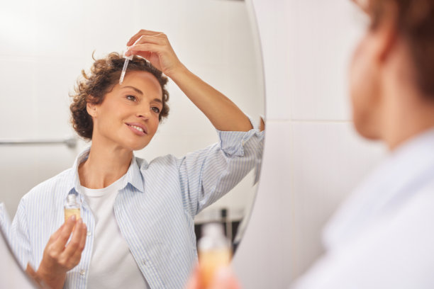 女性在浴室里用滴管涂抹头发精华图片下载