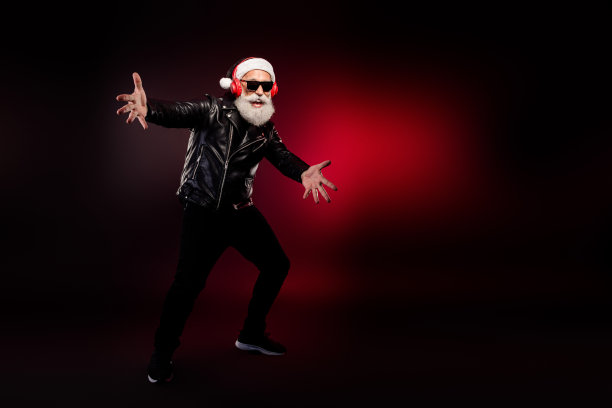 酷炫的圣诞老人摇滚歌手，身穿皮夹克和帽子，戴着红色耳机，在红灯下动感地摆姿势，用于圣诞节素材图图片下载