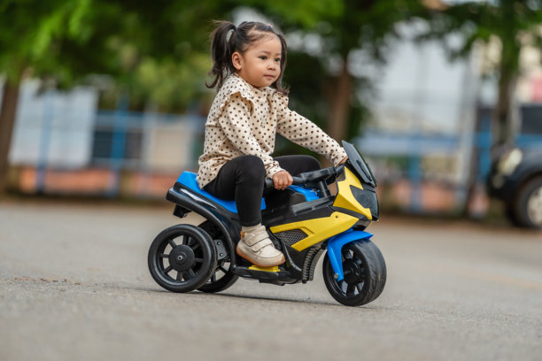 小女孩在公园里骑着电动玩具摩托车图片下载