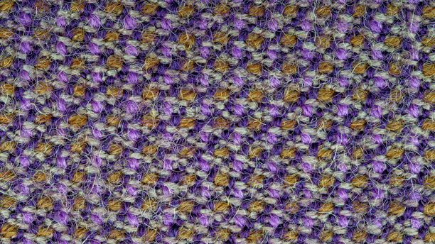 紫、灰、橙色线混合制成的织物纹理的微距照片，可用作背景。该织物由合成纤维和羊毛混合而成。抽象图案。图片下载