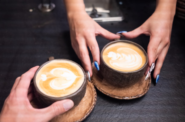情侣在咖啡馆享用带有拉花艺术的咖啡图片下载