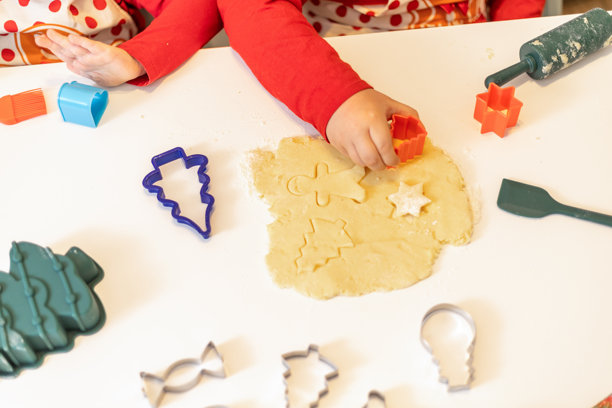 孩子们在家中进行有趣的烘焙活动，在白色桌子上用色彩缤纷的饼干模具和面团制作节日饼干图片下载