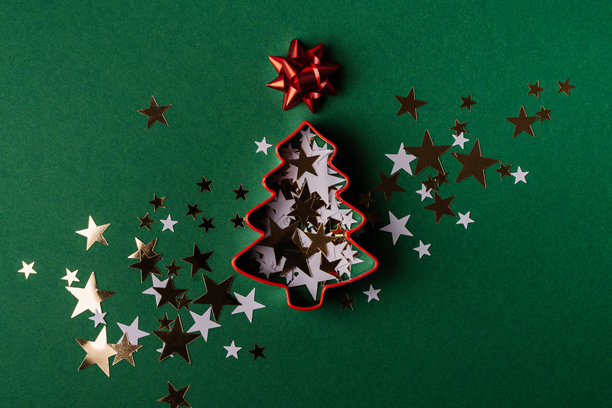 圣诞树饼干模具和星星纸屑在绿色背景上图片下载
