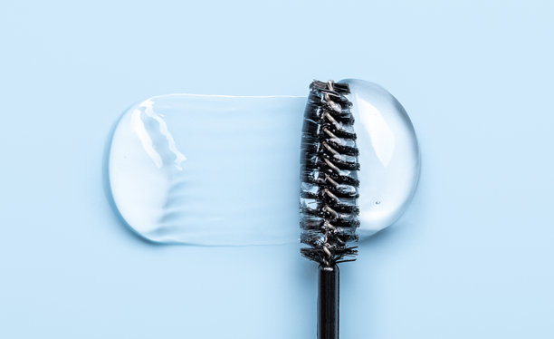 透明眉毛和睫毛凝胶精华的特写照片，质地光滑有光泽，背景为蓝色图片下载