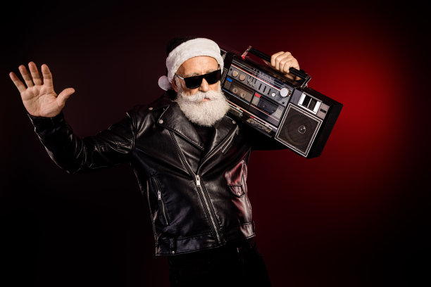 摇滚风的圣诞老人身穿皮夹克，手提录音机，充满节日活力地摆姿势，适合圣诞和音乐主题的素材照片图片下载