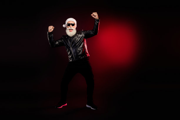 身穿皮夹克的动感摇滚圣诞老人，在戏剧性的红色灯光下摆姿势，用于节日素材图图片下载