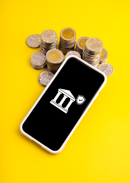 带有银行图标和盾牌的智能手机屏幕上显示着硬币堆，代表在线银行、安全金融交易、移动安全、兑换、数字金融和金融科技解决方案。图片下载