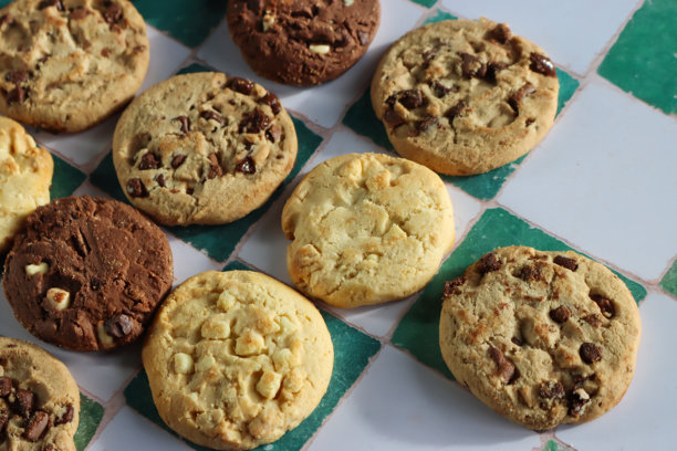 白色和绿色格子背景上巧克力碎曲奇饼干的特写图片，节日三倍巧克力碎，牛奶巧克力碎和白巧克力碎饼干，俯视角度图片下载
