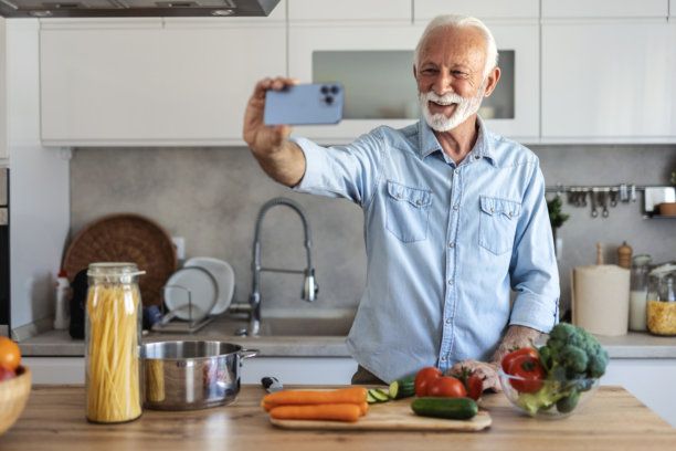 成熟男子在家准备食物时自拍。男子在厨房准备食物时自拍的照片。图片下载
