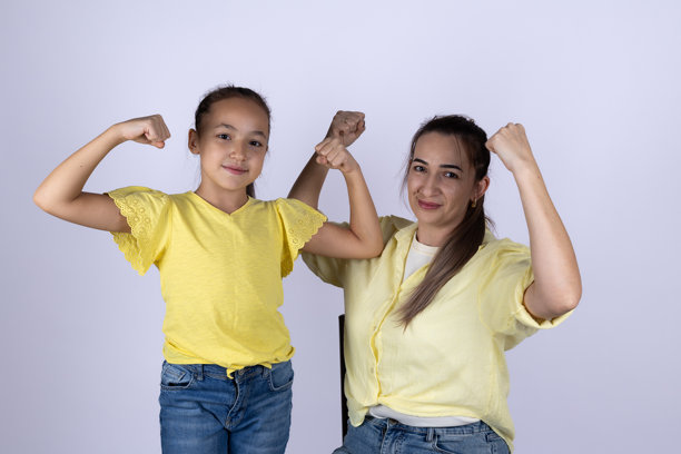 一位女士和一位小女孩正对着镜头微笑，展示着她们的手臂肌肉图片下载
