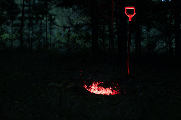 黑暗中，一把红色的铲子被照亮。这张照片带有一种黑暗而神秘的氛围。图片下载