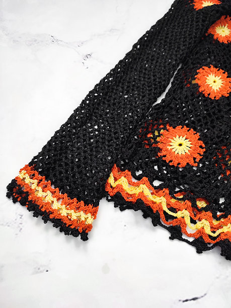 黑色网状镂空钩针奶奶方块花纹纹理特写，背景为灰色。橙黄色钩针花卉图案，爱好。手工编织毛衣，复古风格，编织创意图片下载