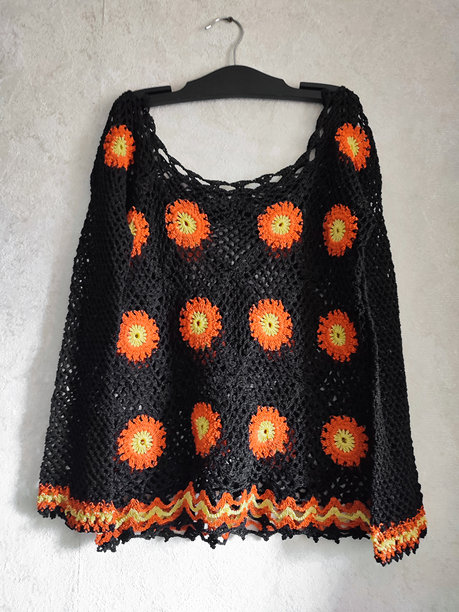 黑色镂空钩针奶奶方块花朵露肩长袖上衣挂在衣架上，灰色背景。橙黄色钩针图案，钩织，爱好。手工编织毛衣，复古风格，编织创意图片下载