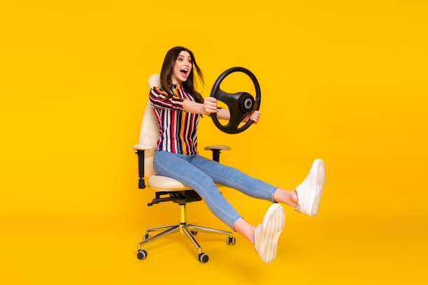 年轻女孩驾车旅行，手握方向盘，脸上带着快乐的笑容，全尺寸侧面照片，孤立在黄色背景上图片下载