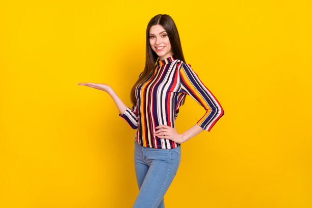 年轻女孩侧面照片，面带快乐积极的微笑，展示新产品，促销广告，隔离在黄色背景上图片下载