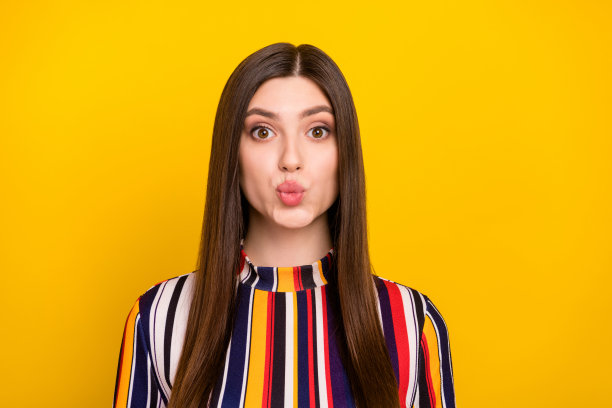 照片肖像：漂亮的女孩在鲜艳的黄色背景前送飞吻，在约会中图片下载