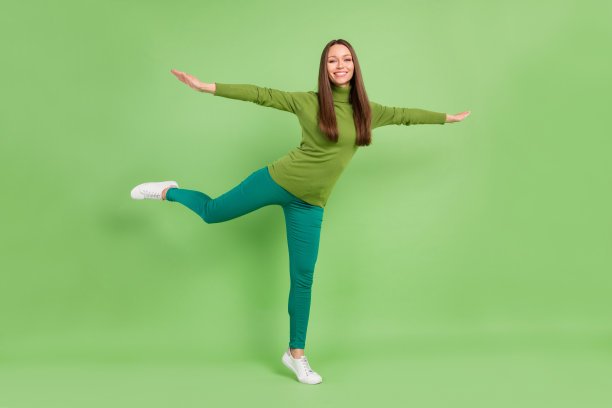 一名年轻女子手扶飞机翅膀，面带喜悦的笑容，背景为绿色，全尺寸照片图片下载