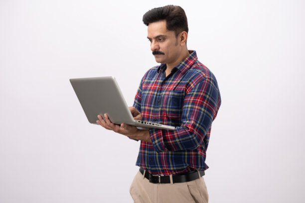 英俊的中年男性穿着格子衬衫，使用笔记本电脑，在白色背景下拍摄的素材照片图片下载