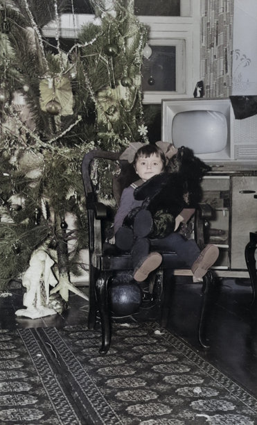 一位甜美小女孩的复古肖像，她坐在古董椅子上，靠近圣诞树，怀里抱着一只泰迪熊。这是一张摄于1972年的复古照片。图片下载