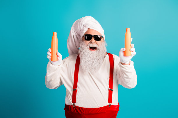 一位穿着红吊带、戴着毛巾帽、手拿橙色瓶子的搞笑圣诞老人模仿者，为圣诞主题的素材图片营造了节日气氛图片下载