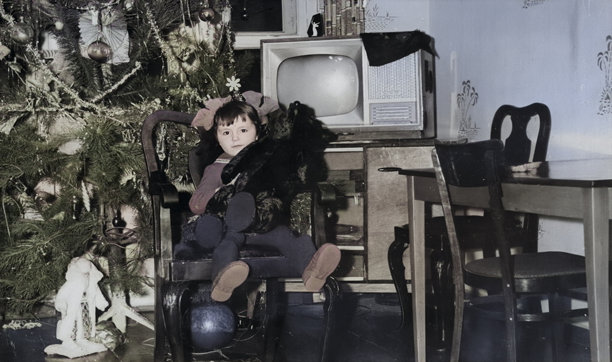 一位甜美小女孩的复古肖像，她坐在古董椅上，怀里抱着泰迪熊，旁边是圣诞树。摄于1972年的老照片。图片下载