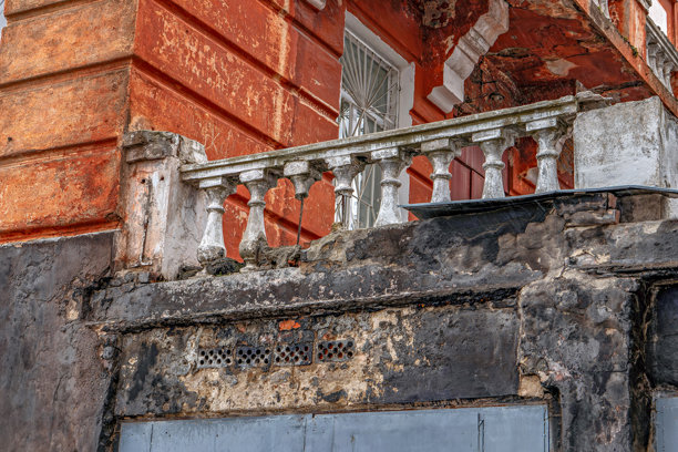 图片展示了一座破败的建筑，其阳台的油漆剥落、生锈，显示出被忽视和年代久远。图片下载