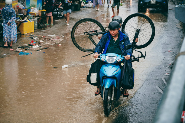 越南人民在亚洲的连日暴雨导致芽庄市街道被淹后，骑摩托车穿过水坑撤离。图片下载