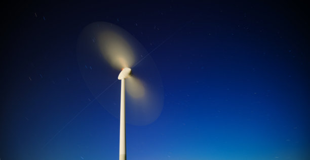 夜空下的地球视角，长曝光拍摄的移动风力涡轮机、星辰和国际空间站——象征科技发展、能源与动感——摄于德国慕尼黑图片下载