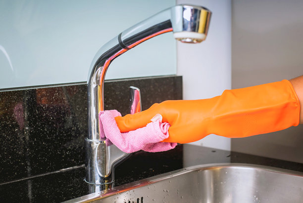 戴手套的手用橡胶清洁厨房水龙头图片下载