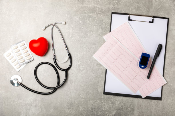 医疗听诊器、红色心脏和心电图在彩色背景上。心电图，心跳波形，心脏病发作，心电图报告。心电图脉搏痕迹和心脏概念。医疗保健。留有文本空间图片下载