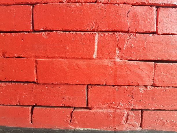 色彩鲜艳的红色砖墙，带有细微的裂纹；统一涂刷的红色砖墙的满幅画面；粗糙纹理的红色砖背景图案特写。图片下载