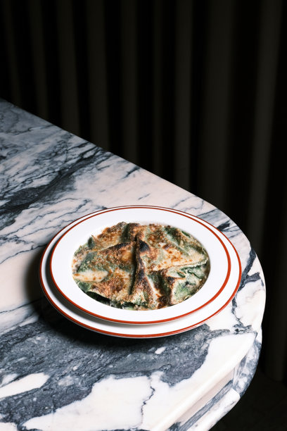 大理石桌上烤宽面条的特写俯视，配有菠菜意面片和焦黄的奶酪层，餐厅环境中的传统意大利舒适菜肴，菜单视觉和美食品牌推广的烹饪概念图片下载