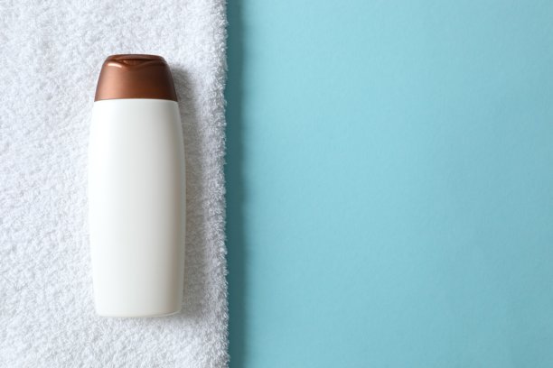 蓝色桌子上白色化妆品洗发水瓶子模型，配有浴巾，特写图片下载