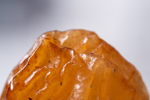 一张极致的微距照片，揭示了葡萄籽复杂的多层表面，其特征是深邃、蜡质、半透明的褶皱和卷曲，呈现出琥珀色和黄褐色。图片下载