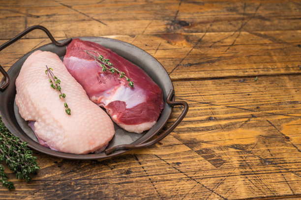 带皮和去皮的生鸭胸肉，配以百里香，放在乡村木桌的金属锅中，是制作美食禽肉烹饪素材图片的理想选择。图片下载