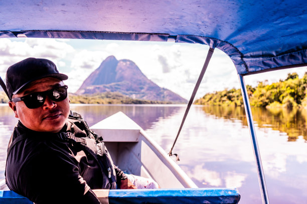 男人在亚马逊地区驾船探索风景如画的山地景观图片下载