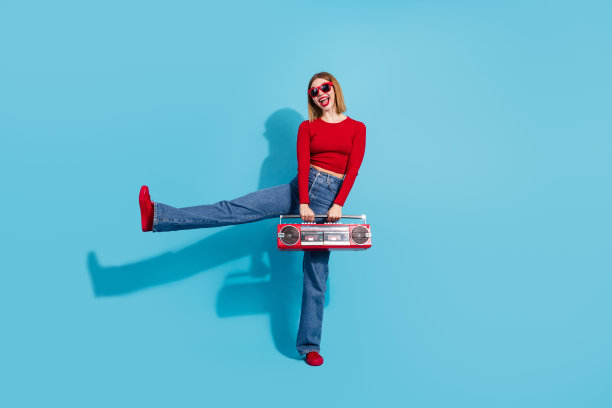 一位时尚年轻女子，背景为蓝色，手持复古收音机，展现出活力四射的风格与魅力图片下载
