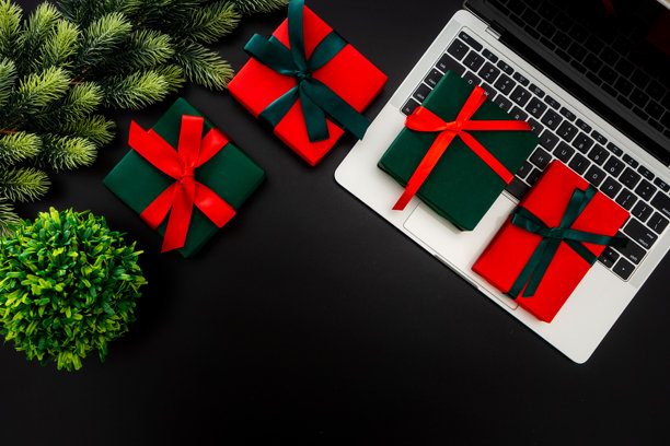 俯视视角，圣诞风格的工作空间，黑色背景上放有笔记本电脑和装饰性礼物。自由职业和节假日工作概念。图片下载