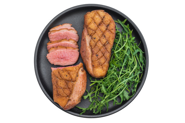 精致烤鸭胸搭配蔬菜，置于深色盘中，背景为干净的灰色台面，非常适合美食博客和摄影素材。图片下载