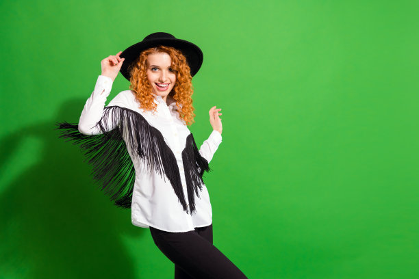 一位迷人的、酷炫的、时髦的、快乐的女孩，情绪饱满，尽情舞动，在明亮的绿色背景前，表情愉悦图片下载