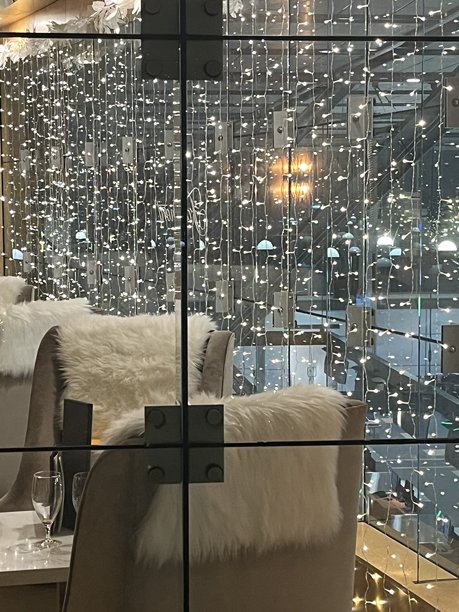 柔和的灯光和蓬松的座椅营造出城市用餐空间的温馨氛围，背景中闪烁的灯光在夜晚熠熠生辉。图片下载